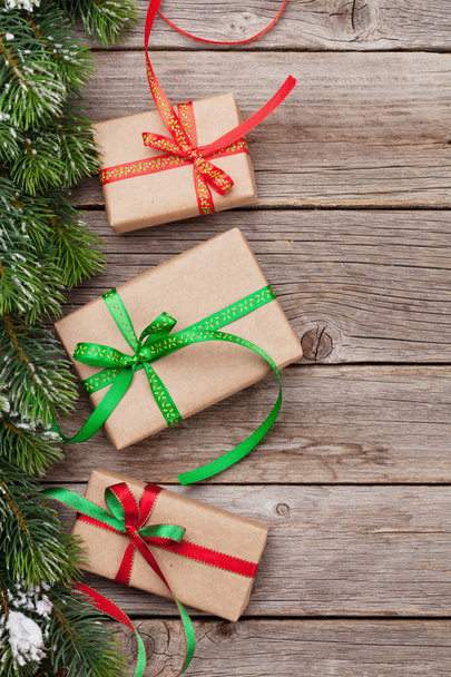 Cajas de regalo de Navidad y abeto de nieve en mesa de madera. Vista superior con espacio para tus saludos
 - Foto, Imagen
