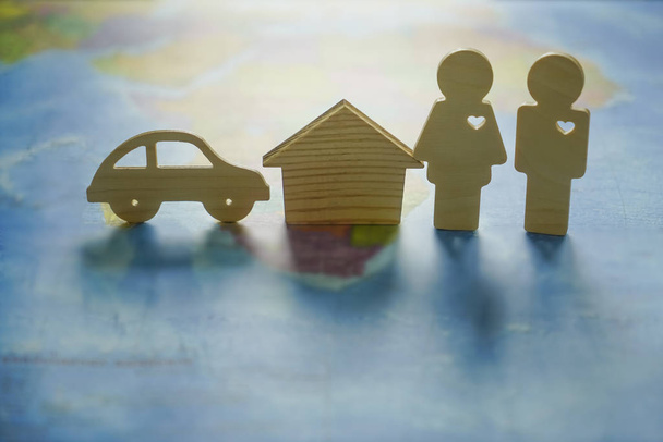 wooden figures - couple, house, car on paper world map.  - Foto, imagen