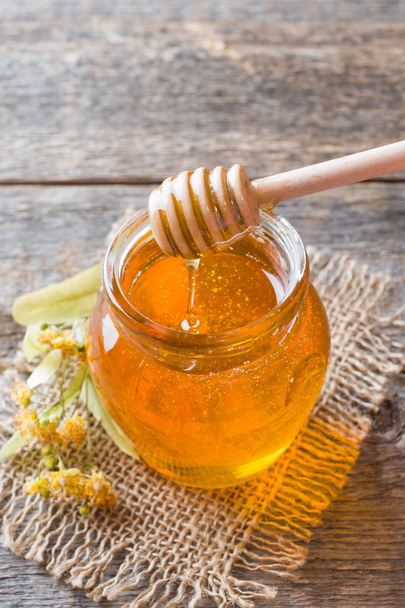 Glass jar of honey, Linden flowers on wooden background - Фото, зображення