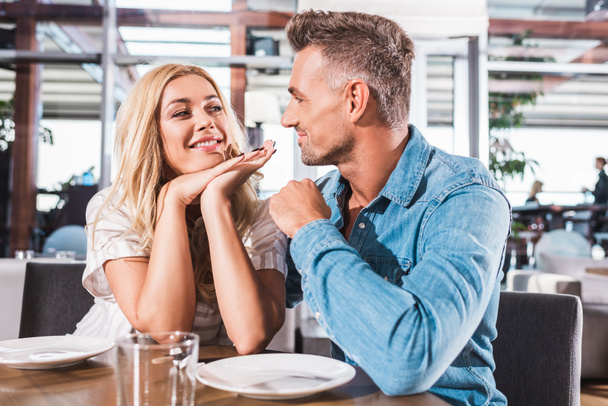 happy couple looking at each other at table in cafe - Photo, Image