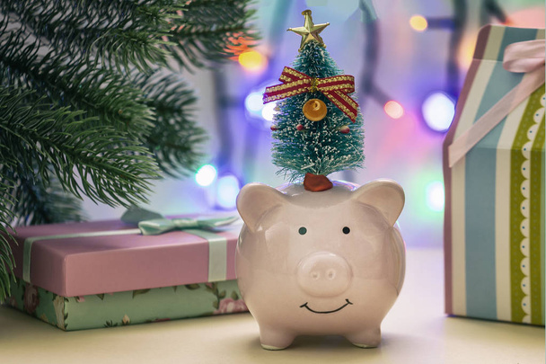 Piggy bank met boom op kop in de buurt van geschenken  - Foto, afbeelding