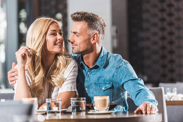 happy romantic couple hugging at table in restaurant - Photo, Image