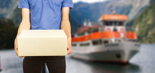 Mann hält Kiste mit Schiff im Hintergrund - Foto, Bild