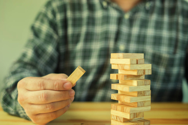 man playing wood blocks tower game jenga in office - 写真・画像