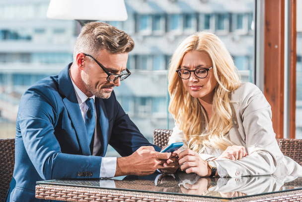 üzleti partnerek használ smartphone ülésen kávézóban portréja - Fotó, kép
