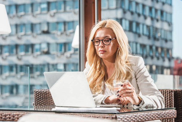 blonde femme d'affaires dans les lunettes à l'aide d'un ordinateur portable dans le café
 - Photo, image