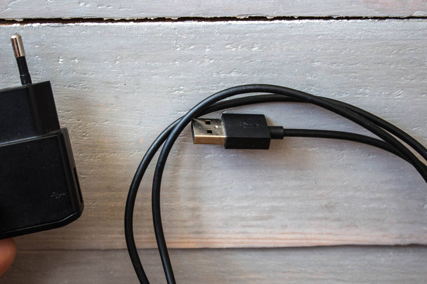 USB-шнур с зарядным устройством на деревянном фоне
 - Фото, изображение