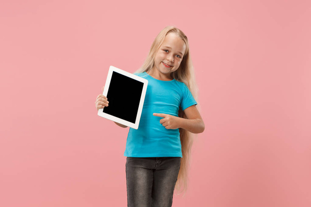 Little funny girl with tablet on pink background - Foto, Imagen