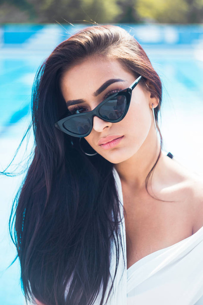 Glamour portrait of young and beautiful woman sitting by the pool - Foto, Bild