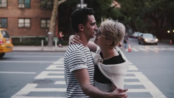 Slow motion happy young Hispanic man hugging and dancing with European girlfriend near New York busy street crossing. - Video, Çekim