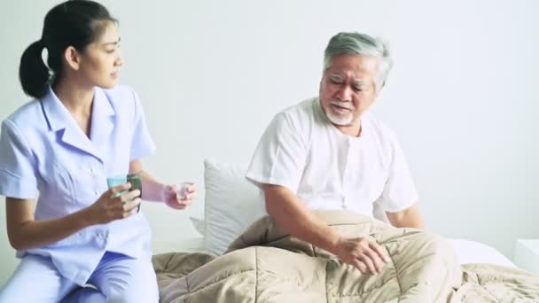 nurse bringing medication and water to upset mature asian man in hospital - Filmati, video