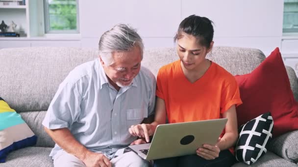 asian granddaughter helping her grandfather using computer indoors - Filmati, video