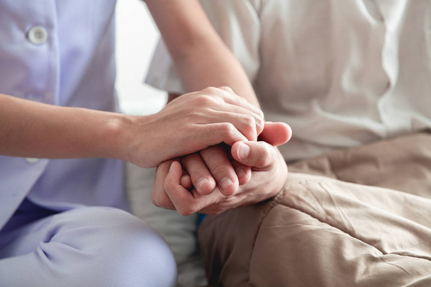 Comforting hand. Young nurse holding old man's hand. Senior care, care taker and senior retirement home service concept. Close up shot. - Fotoğraf, Görsel