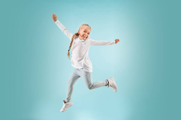 Очаровательный маленький ребенок в голубой студии. Девушка прыгает и улыбается
. - Фото, изображение