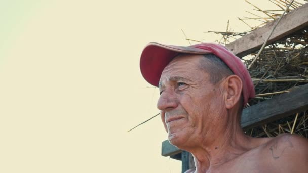 Портрет курящего трудолюбивого на фоне сельской местности. Фермер в кепке курит сигарету
 - Кадры, видео