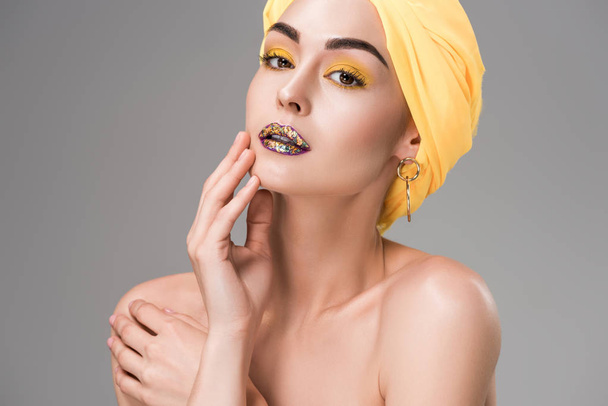 beautiful naked girl with stylish makeup wearing yellow turban and looking at camera isolated on grey  - Foto, Imagem