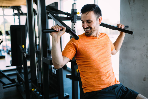 Fit handsome man exercising at the gym on a machine - Fotó, kép