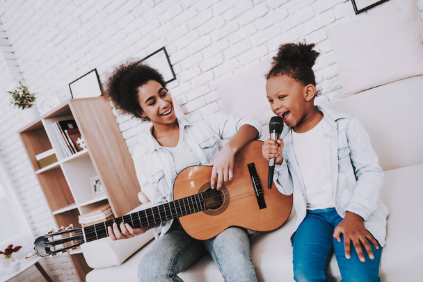 Happy Young Mother and Happy Sister Play in the Guitar. Education for Little Girl and Young Mother. Time with Family. Happy Family Together. Mulatto with Mother Happy Time Together. Funny Girl and Mom - Fotó, kép
