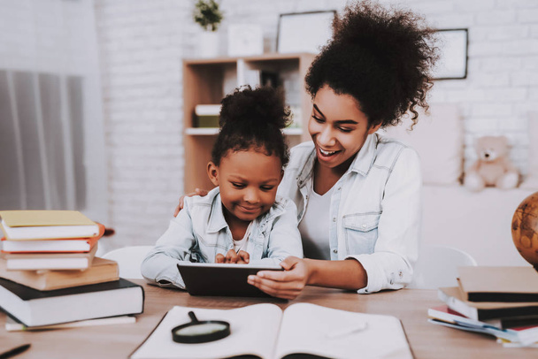 Mulatto Mother and Milatto Girl Time Together. Love Mother and Love Girl Watching in Tablet. Young Child. Study and Help Little Girl with Test. Work for Girl and Mother. Smile Girl and Young Mother. - Fotoğraf, Görsel