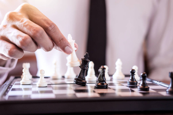 Hand of confident businessman use king chess piece white playing chess game to crash overthrow the opposite team and development analysis new strategy plan, business strategy for win and success. - 写真・画像