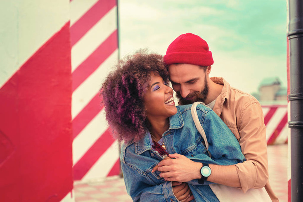 Bearded young man standing behind his beautiful girlfriend and hugging her - Valokuva, kuva