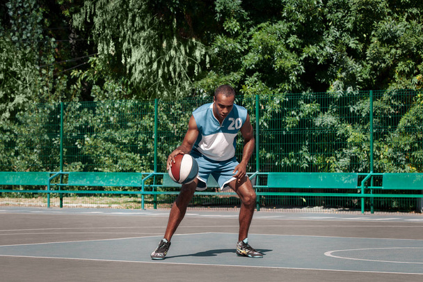 Picture of young confused african basketball player practicing - Фото, изображение