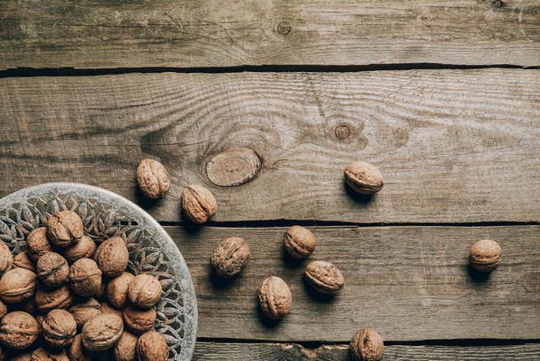 top view of ripe organic walnuts and plate on wooden table - Fotoğraf, Görsel