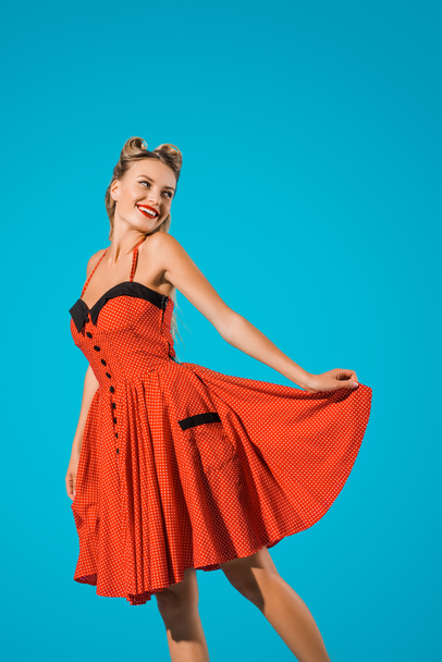 portrait of cheerful pin up woman in retro dress posing isolated on blue - Foto, afbeelding