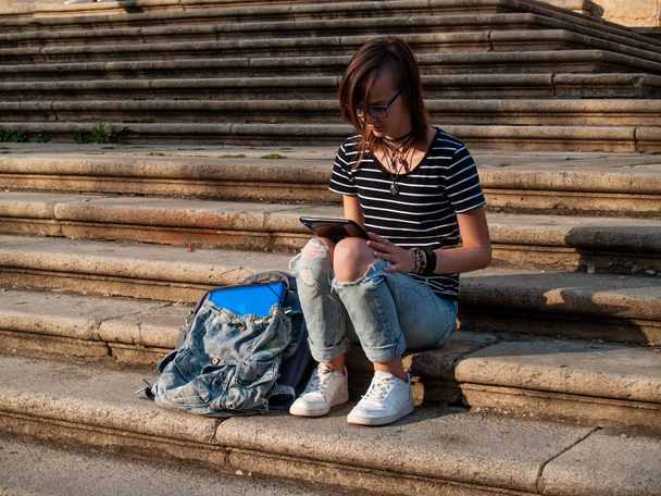 Una adolescente con una tableta en las escaleras de una universidad en un campus universitario
 - Foto, imagen