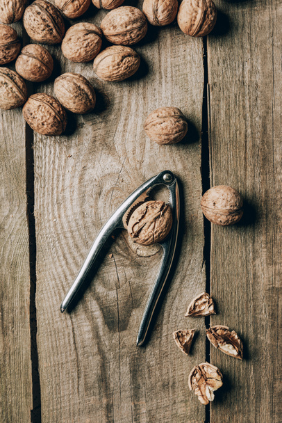 top view of tasty healthy walnuts and nutcracker on wooden table - Fotoğraf, Görsel