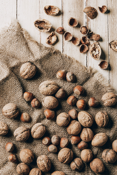 top view of hazelnuts and walnuts on sackcloth on wooden table - Fotoğraf, Görsel