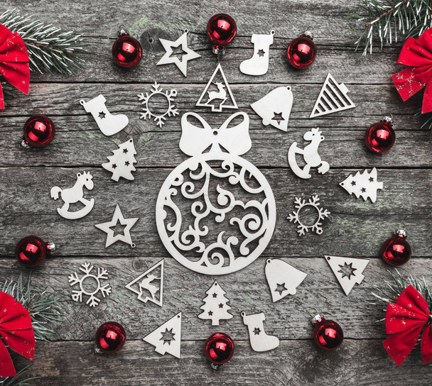 Fenyő ágak piros íjak és a karácsony kézzel készített játékok és a golyó létrehozása egy kört, egy fából készült szürke háttér, karácsonyi üdvözlőlap - Fotó, kép