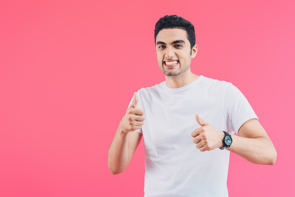 grimacing smiling man showing thumbs up isolated on pink - Fotografie, Obrázek