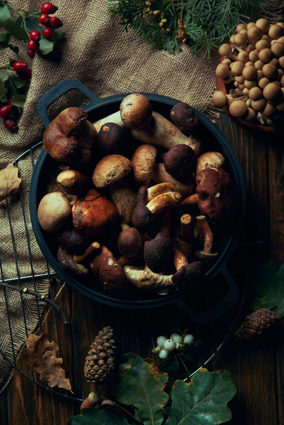 top view of fresh edible mushrooms in pan on wooden table   - Valokuva, kuva