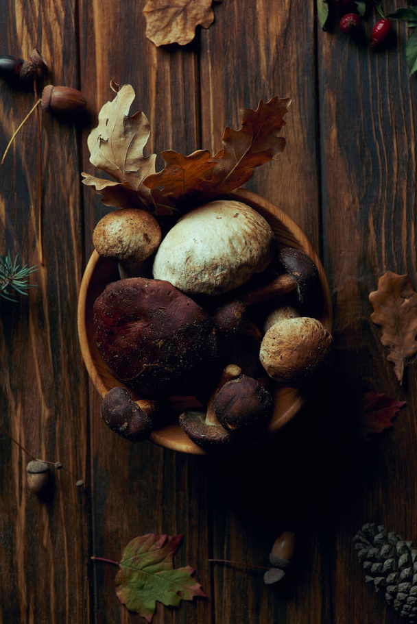 top view of fresh picked natural mushrooms in bowl on wooden table  - Fotoğraf, Görsel
