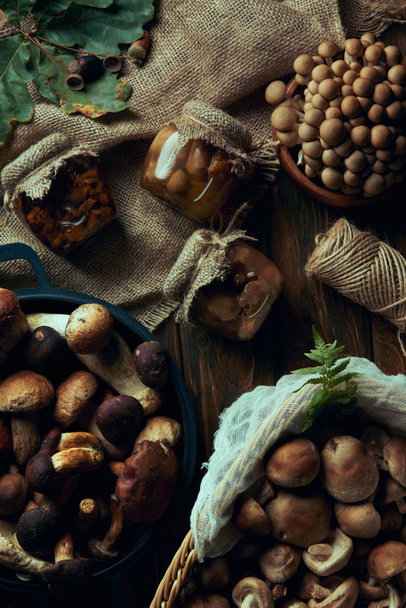 Blick von oben auf leckere frische und eingelegte Pilze aus biologischem Anbau auf Holztisch - Foto, Bild