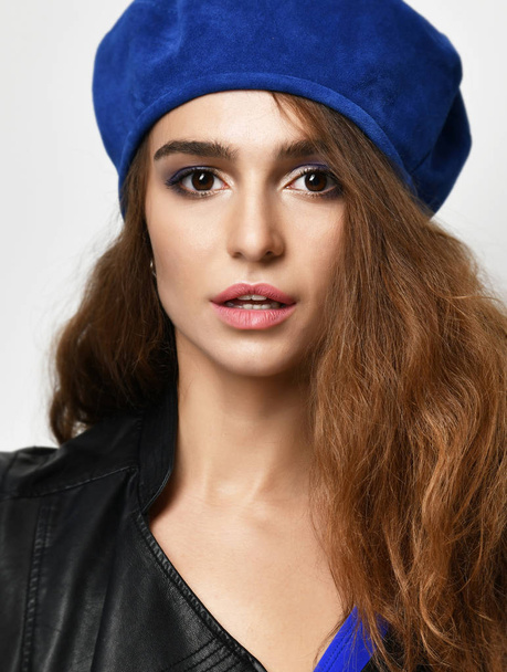 brunette woman in blue beret hat looking at the camera on gray background - Fotó, kép