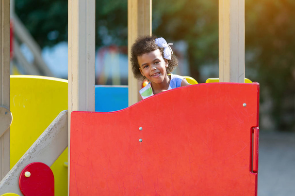 Chica afroamericana juega en el patio de recreo durante el día. Chica negra en el patio de recreo
. - Foto, Imagen