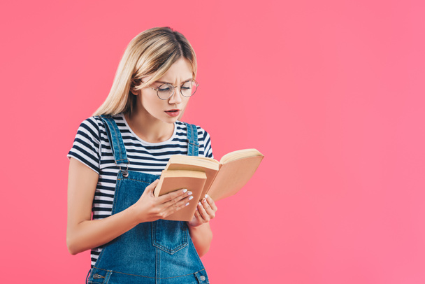 portrait of focused student in eyeglasses with books isolated on pink - Valokuva, kuva