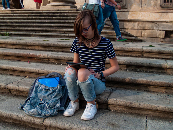 Uma adolescente com um tablet nas escadas de uma universidade em um campus universitário
 - Foto, Imagem