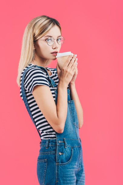 mooie jonge vrouw met koffie te gaan geïsoleerd op roze - Foto, afbeelding