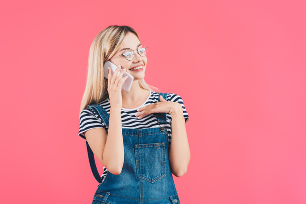 portrait of young smiling woman talking on smartphone isolated on pink - Foto, afbeelding