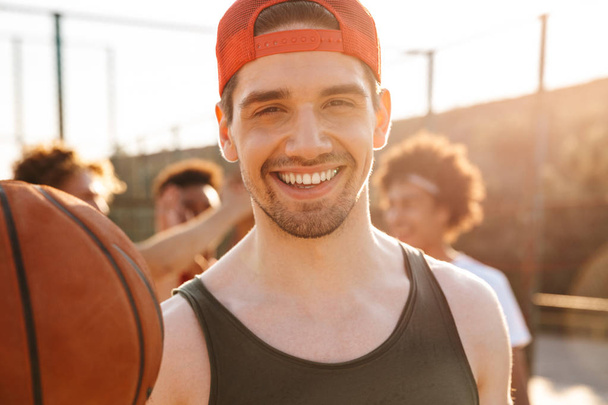 Крупним планом усміхнений чоловік грає в баскетбол зі своєю командою на спортивній арені
 - Фото, зображення