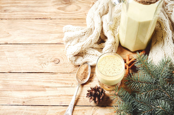 Homemade Eggnog With Cinamon for Christmas and winter holidays on wooden background with spices, spoon and soft knitted warm scarf - Zdjęcie, obraz