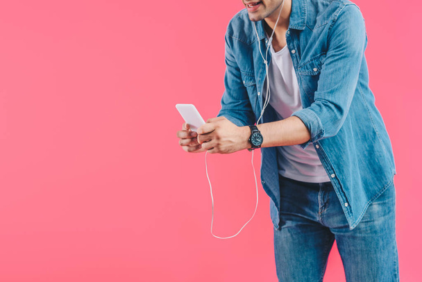partial view of man in earphones with smartphone isolated on pink  - Foto, imagen