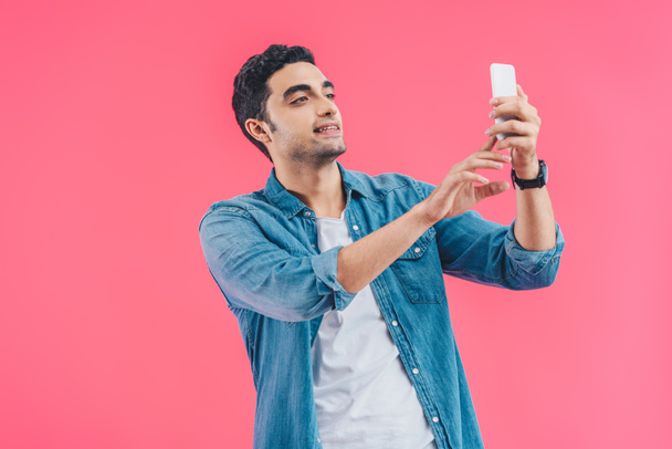 portrait of young man taking selfie on smartphone isolated on pink - Zdjęcie, obraz