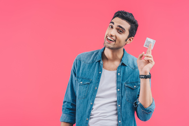 Gelukkig jongeman weergegeven: condoom geïsoleerd op roze - Foto, afbeelding