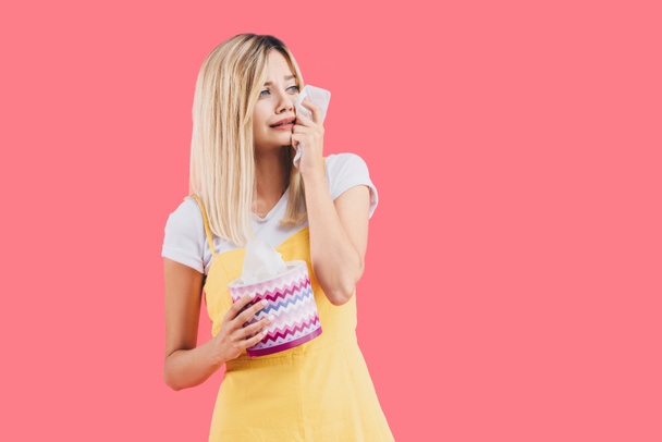 sad young woman with tissue box crying and wiping tears isolated on pink - Photo, image