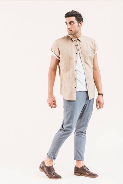 handsome stylish man in shirt posing and looking away isolated on beige - Фото, изображение