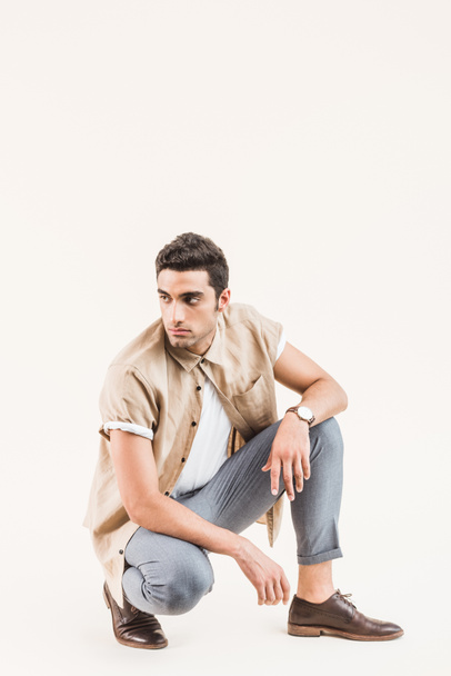 serious stylish young man in shirt sitting isolated on beige - Photo, Image